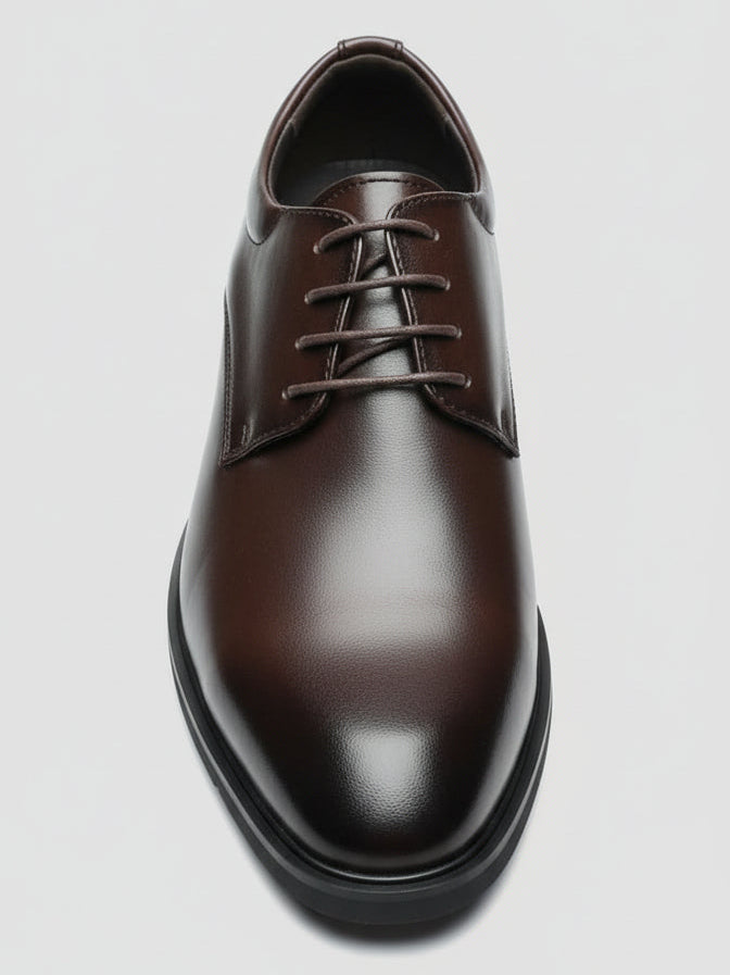 Brown leather shoe held by a hand with a cluttered background
