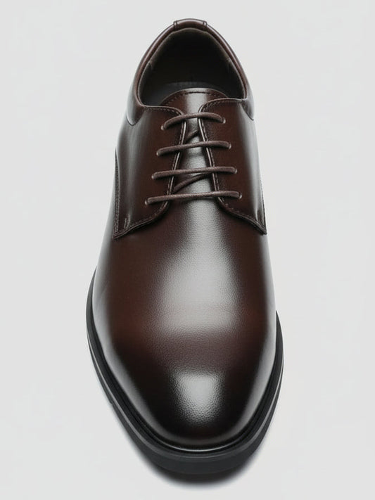 Brown leather shoe held by a hand with a cluttered background