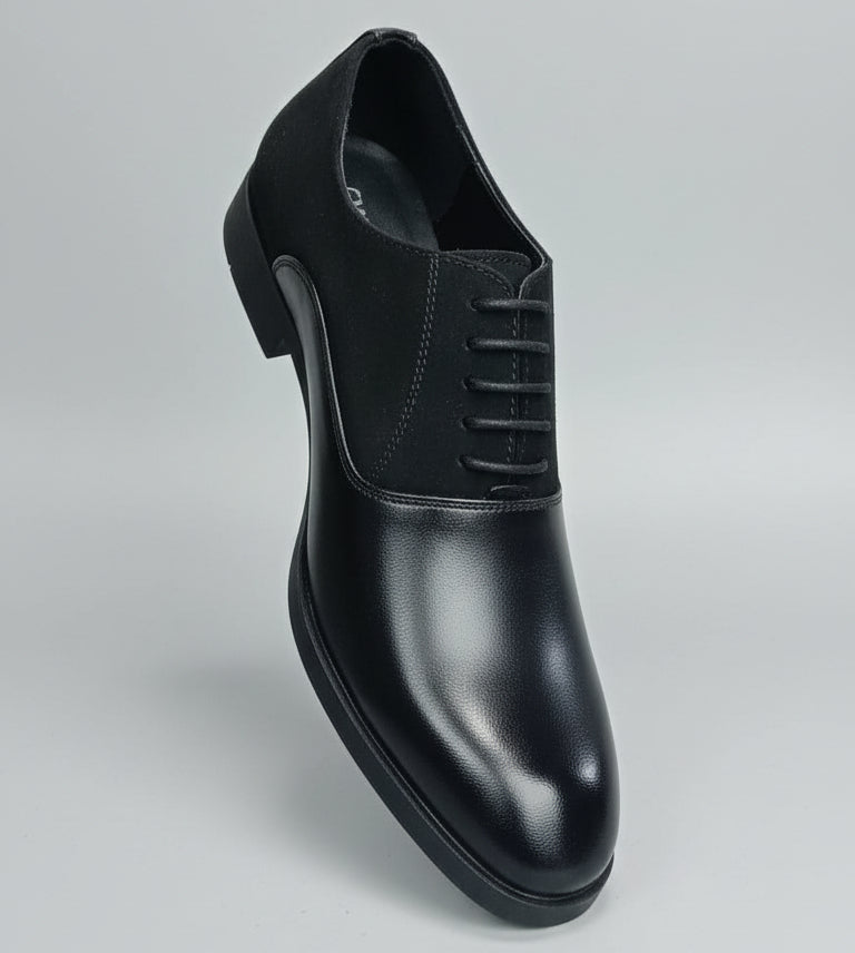 Black leather shoe held in front of a shoe rack with various shoes.