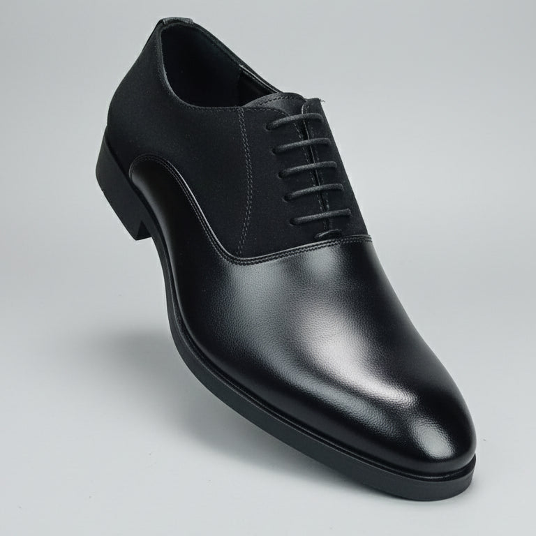 Black leather shoe held in front of a shoe rack with various shoes.