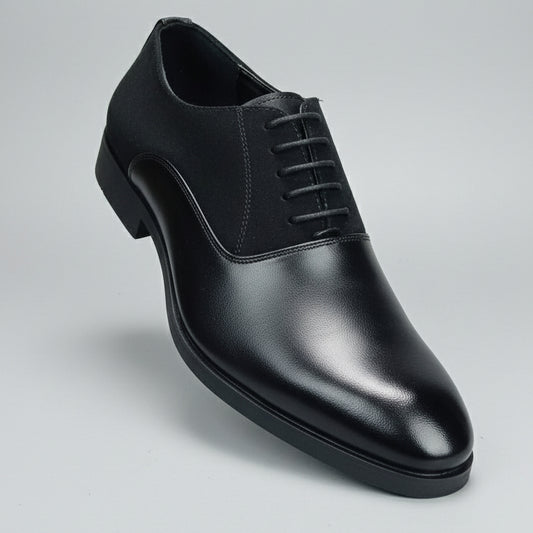 Black leather shoe held in front of a shoe rack with various shoes.