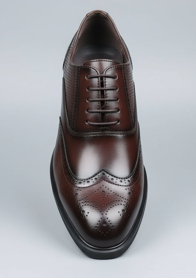 Brown leather shoe held by a hand with a blurred background of shoes and a car interior.